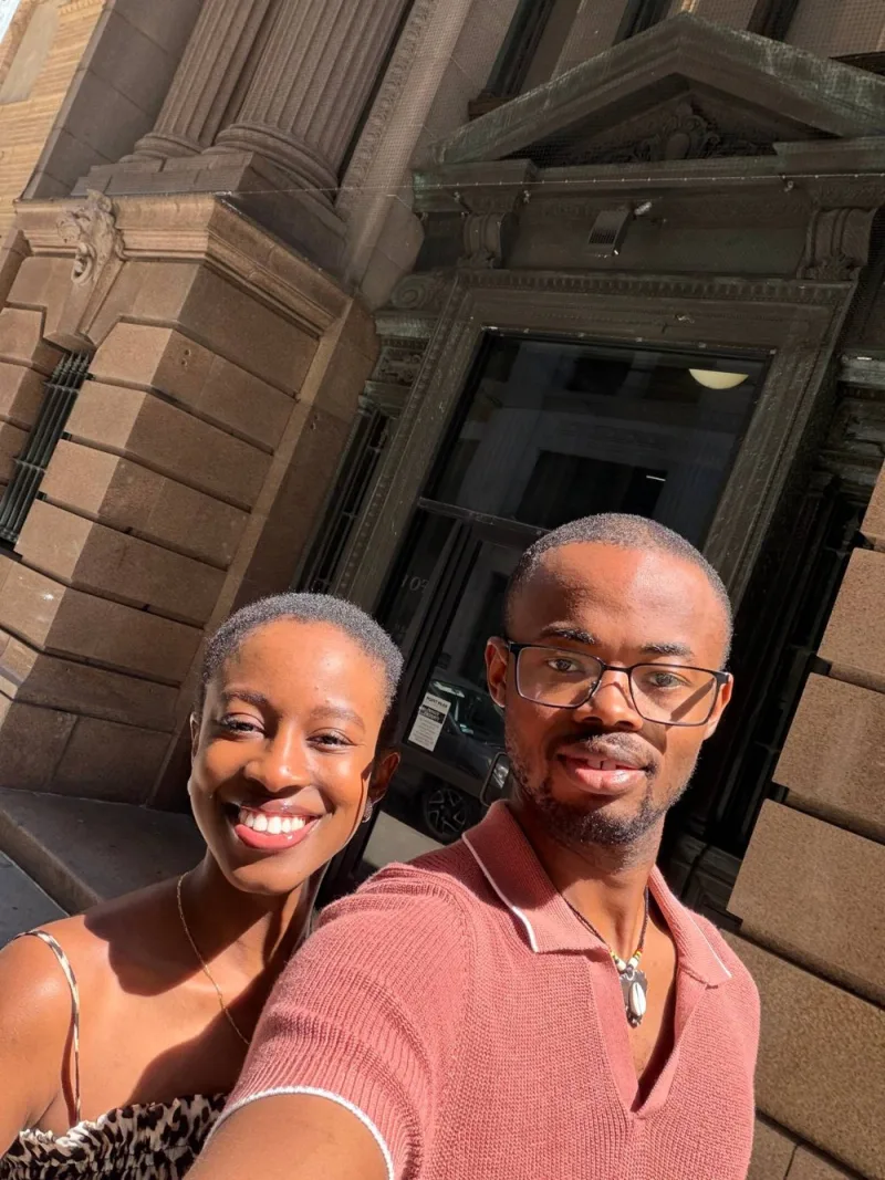 Rafik and Ayesha smiling together in a selfie on a sunny city street